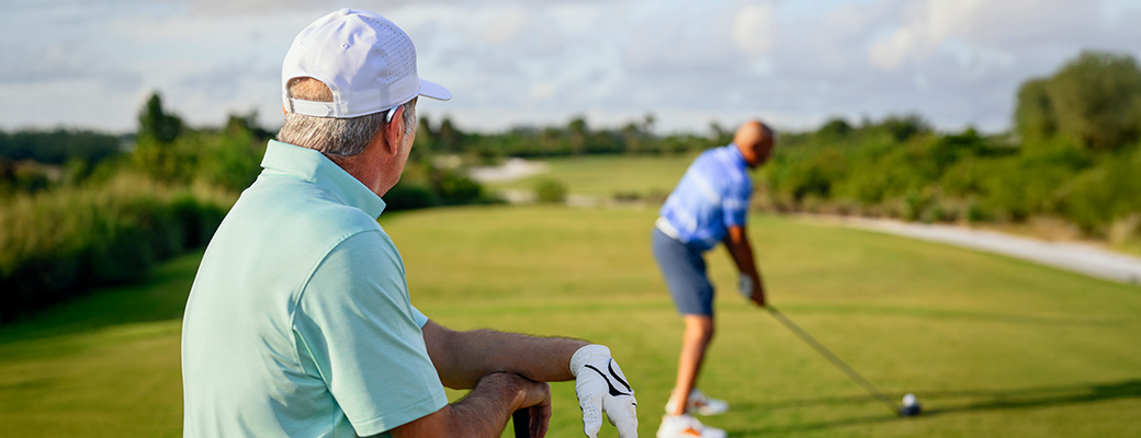 Image of male hearing aid wearer playing golf with another male